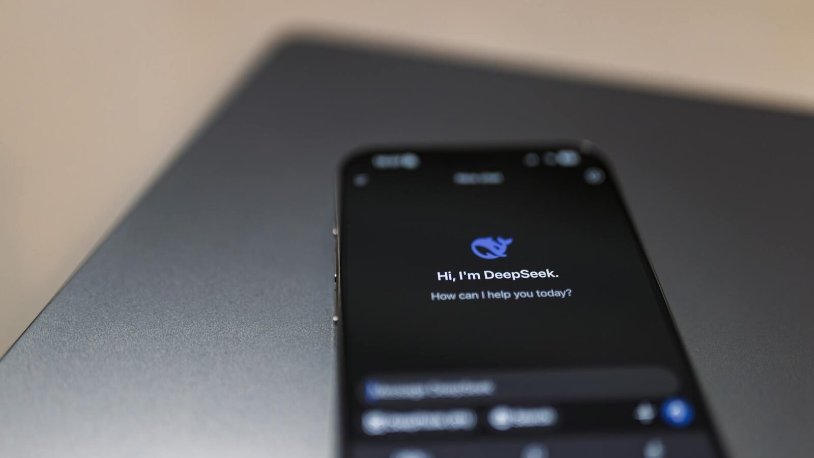 Nahaufnahme eines Smartphones mit KI-Assistentenschnittstelle auf dem Bildschirm über einem Laptop.