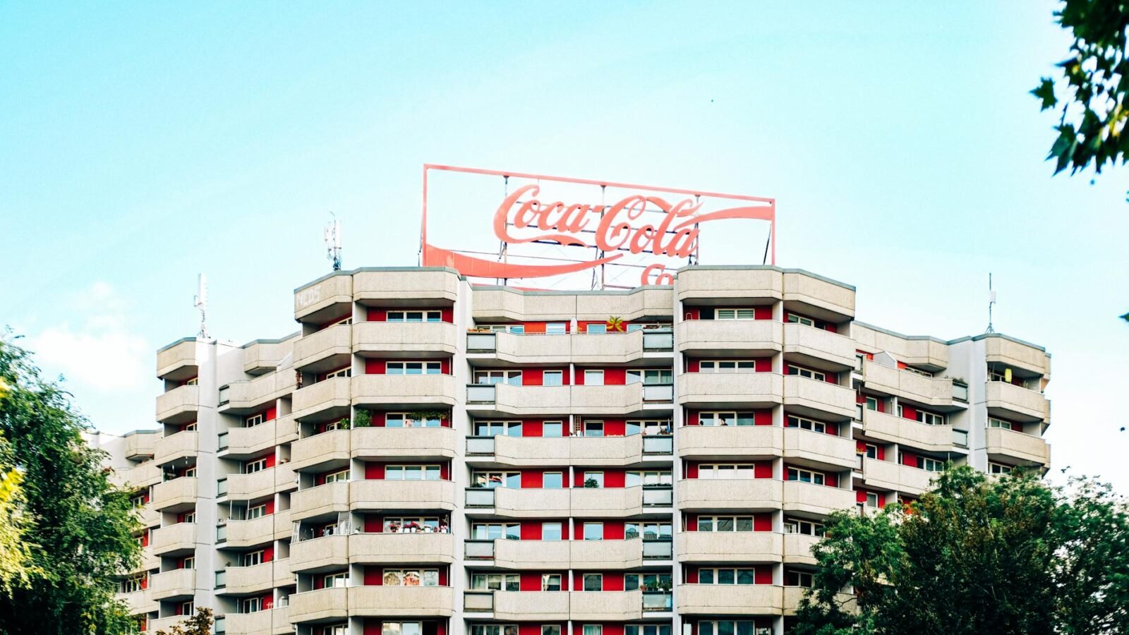 Modernes Stadtgebäude mit Coca-Cola-Schild unter strahlend blauem Himmel.