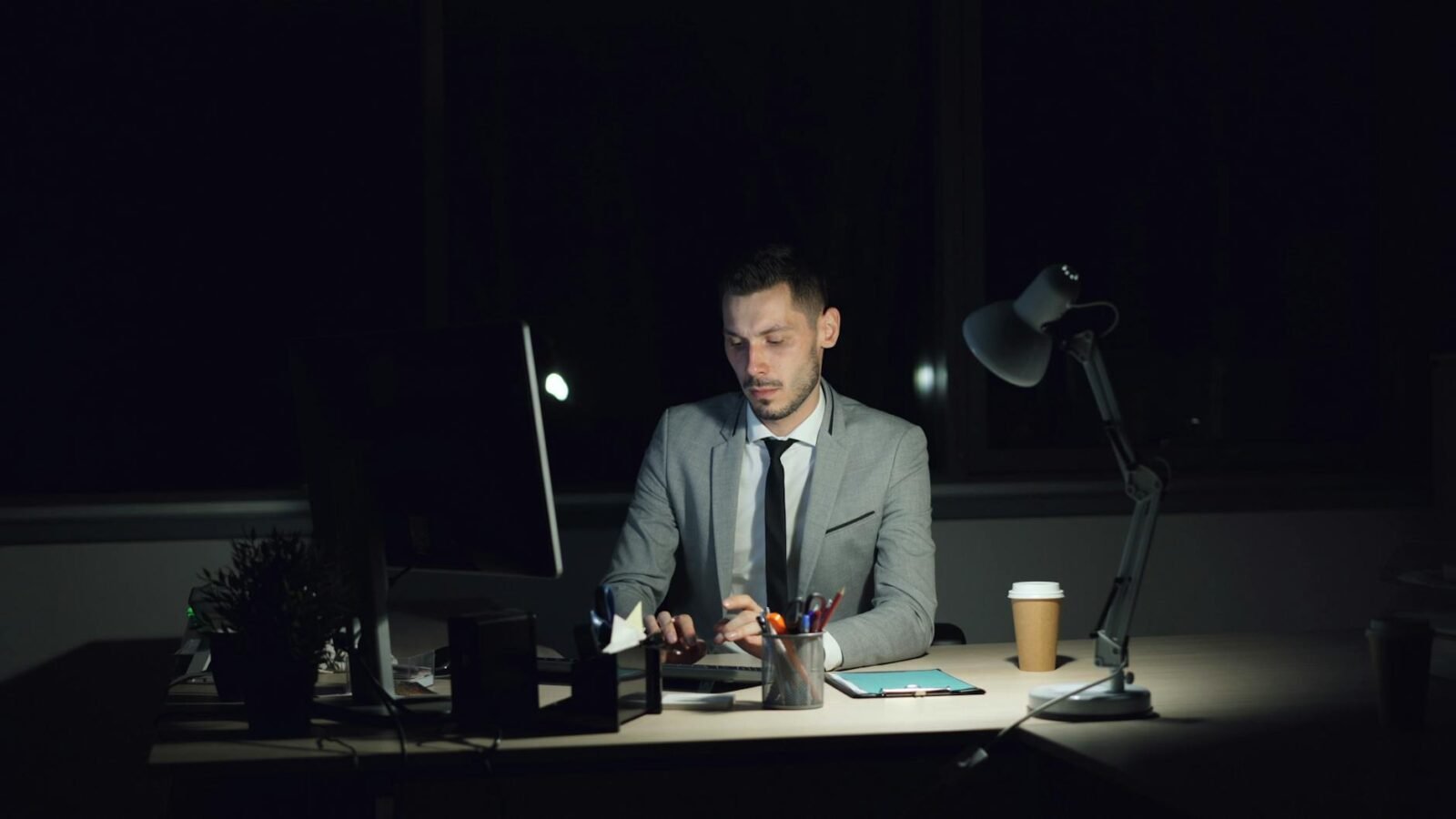 Ein konzentrierter Geschäftsmann arbeitet spät abends in einem schwach beleuchteten Büro.