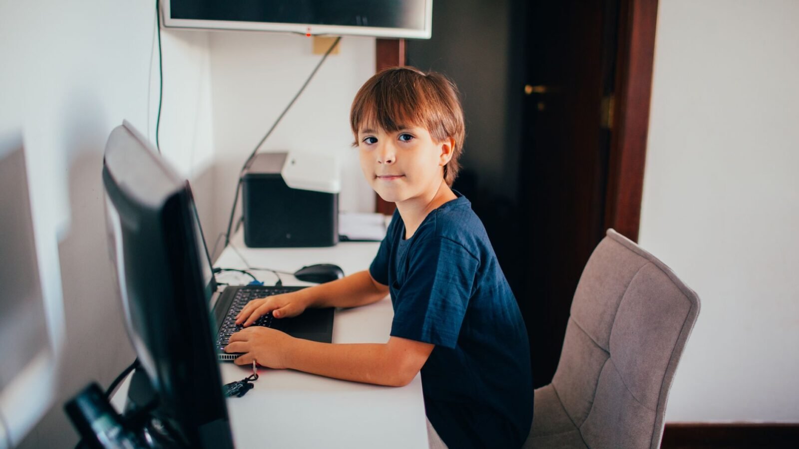 Ein Junge konzentriert sich in seinem Heimbüro auf die Computernutzung. Moderne Technologie und Lernkonzept.